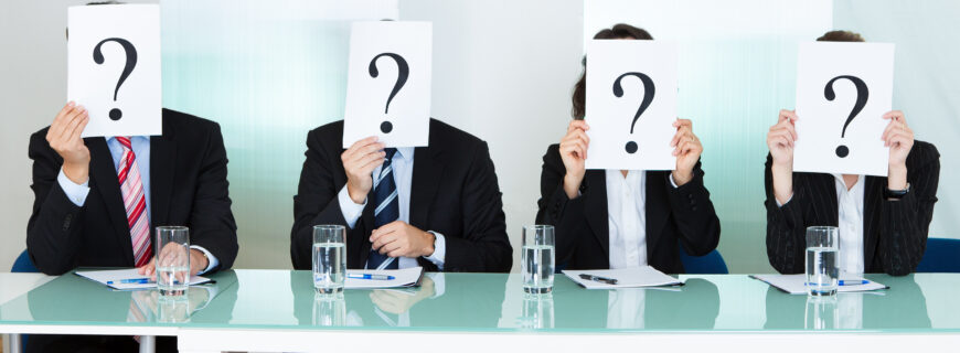 Row of businesspeople with question marks signs in front of their faces